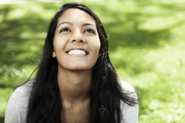 Smiling Hispanic teenager sitting in grass