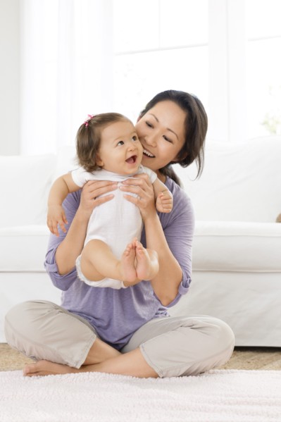Mother playing with baby girl in living room