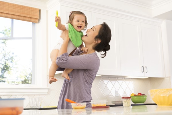 Mother holding baby girl in kitchen