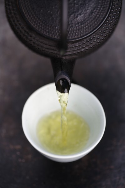 Close up of Japanese green tea being poured from teapot into cup