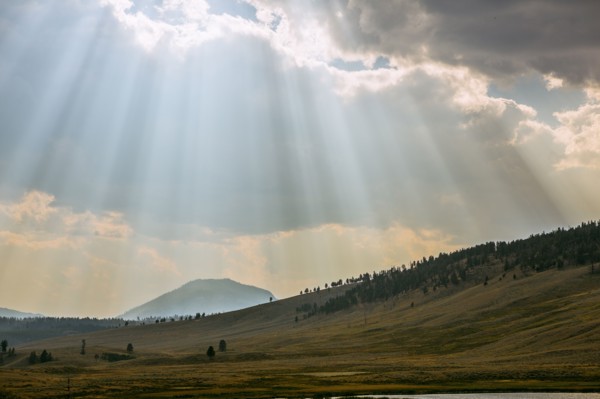 Sunbeams shining through clouds over rolling rural landscape