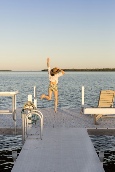 Caucasian woman jumping for joy on pier