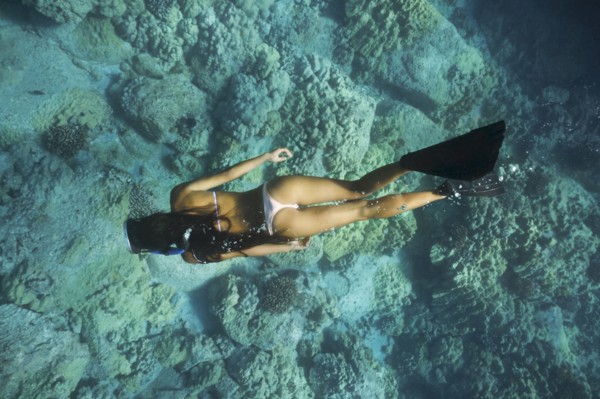 Mixed race woman snorkeling near tropical reef