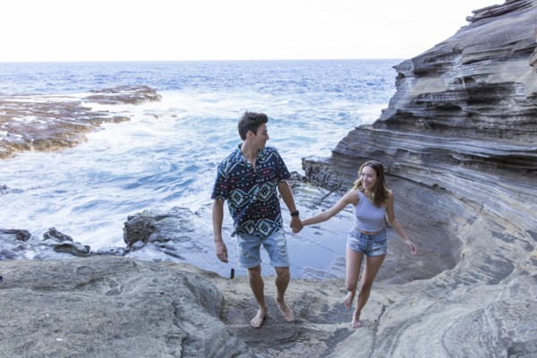 Smiling couple walking on rock formations at beach
