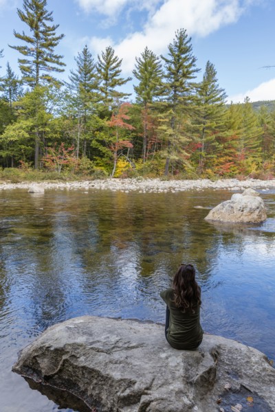Caucasian woman sitting on rock relaxing near river