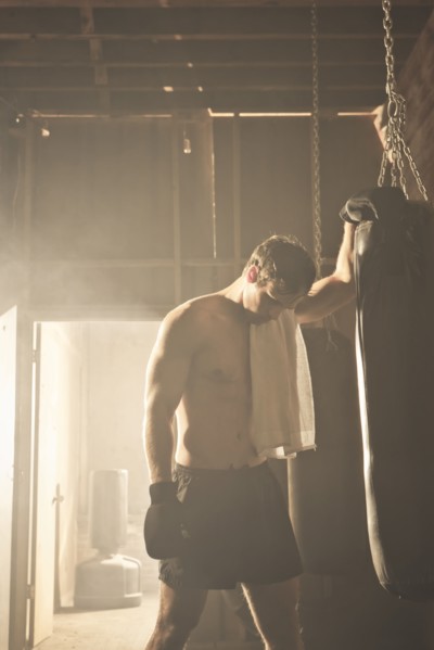Fatigued boxer leaning on punching bag