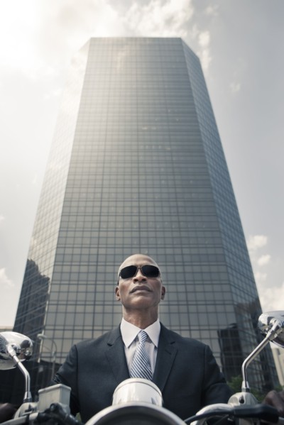 Black businessman riding motorcycle in city
