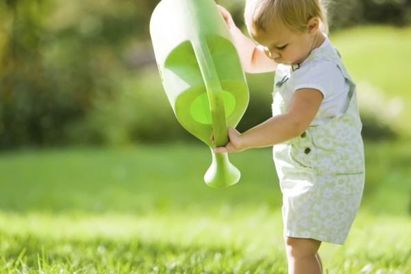Caucasian baby lifting watering can