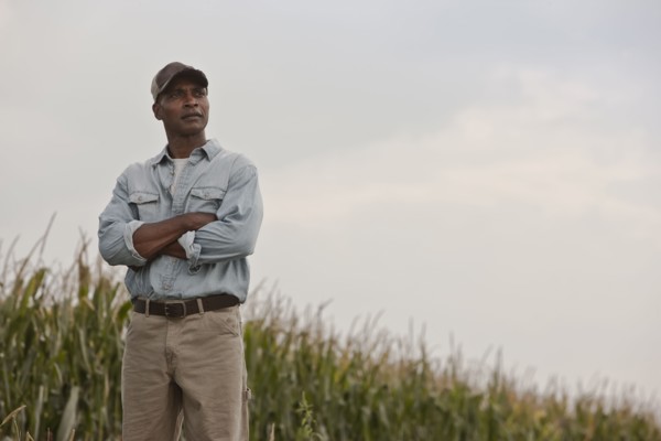 African American man standing in field with arms crossed