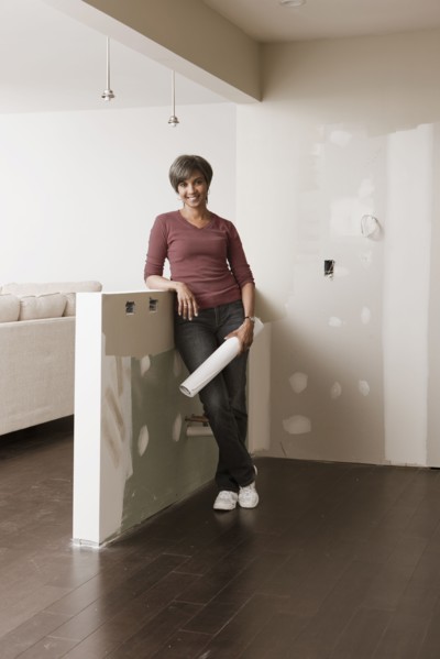 Mixed race woman standing in unfinished room with blueprints
