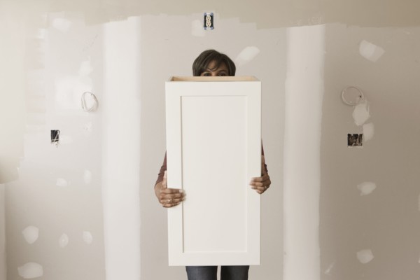 Mixed race woman holding cabinet door in unfinished room
