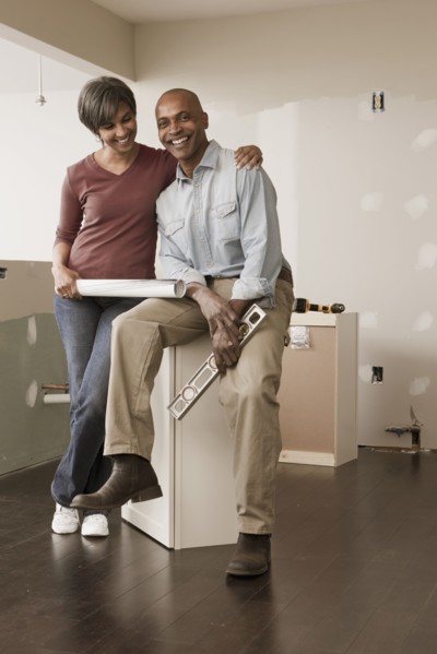 Couple with level and blueprints in unfinished room