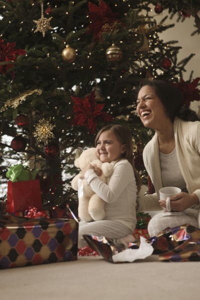 Mixed race mother and daughter opening gifts Christmas morning