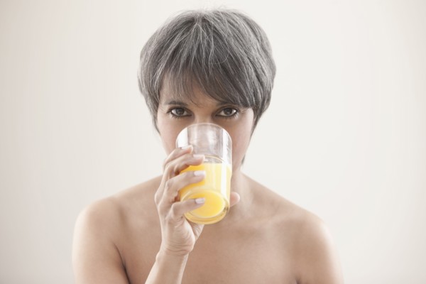 Mixed race woman drinking orange juice