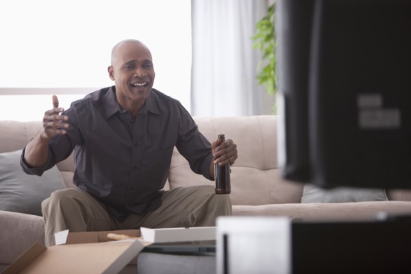 Black man drinking beer and watching television