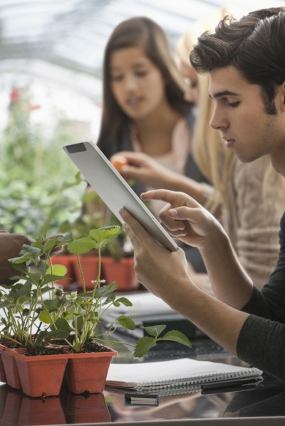 Students working in greenhouse with digital tablet
