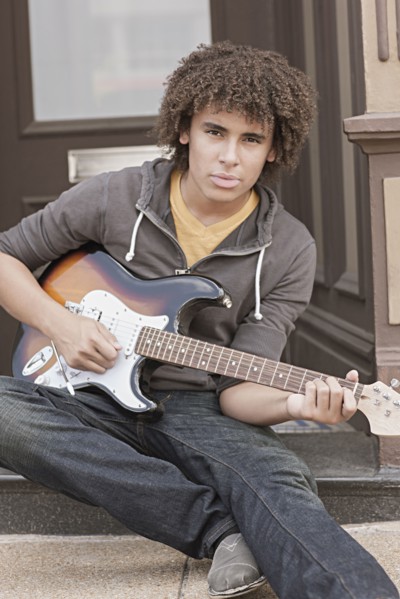 Mixed race teenager playing electric guitar