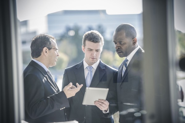 Businessmen using digital tablet outside office