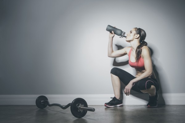 Caucasian woman in sportswear drinking from water bottle