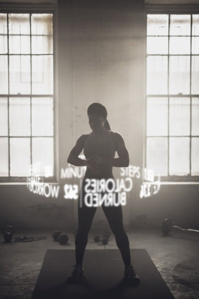 Virtual words circling Black athlete checking fitness tracker