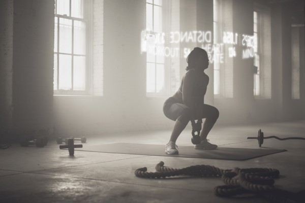 Virtual words circling Black athlete lifting kettlebell