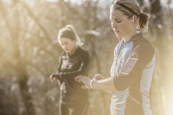 Caucasian runners checking fitness watches in forest