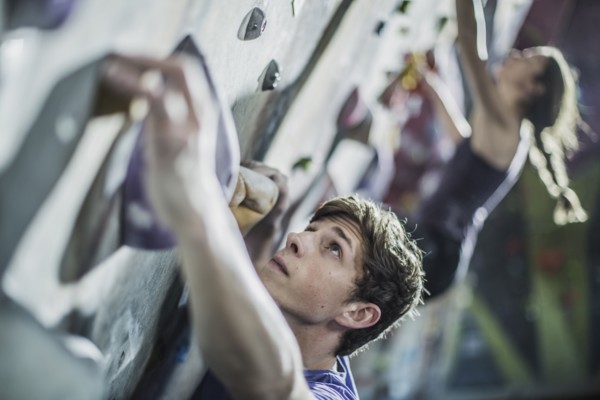 Athletes climbing rock wall in gym