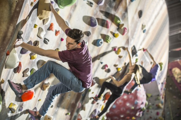 Athletes climbing rock wall in gym