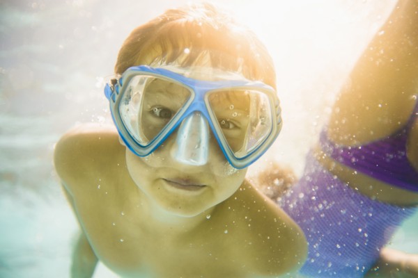 Caucasian boy swimming underwater in swimming pool