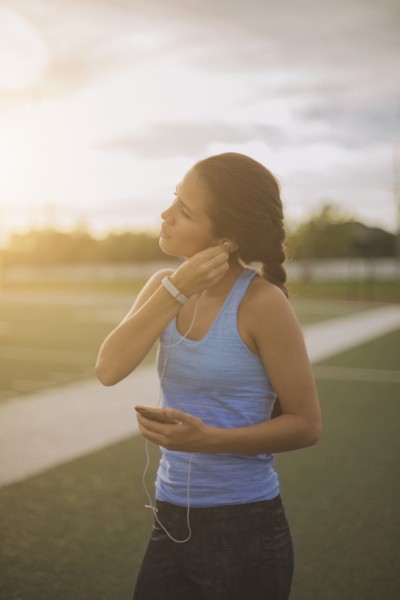 Mixed race athlete listening to mp3 player on sports field