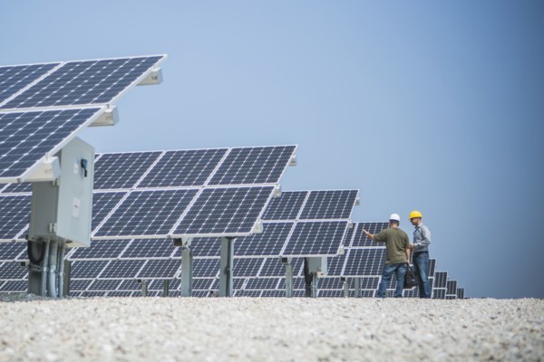 Caucasian technicians talking near solar panels