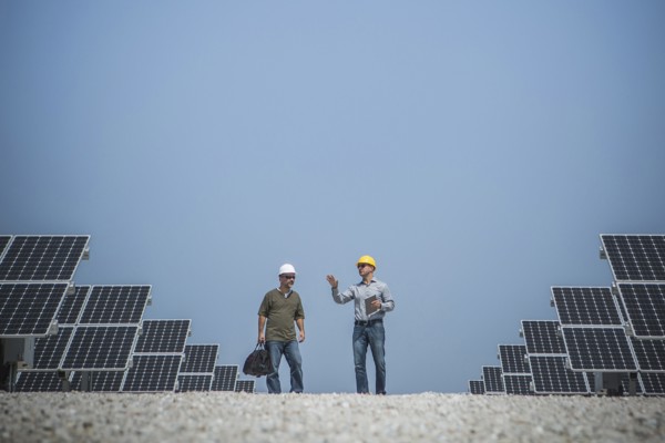 Caucasian technicians talking near solar panels