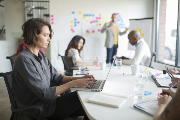 Businesswoman using laptop in office meeting