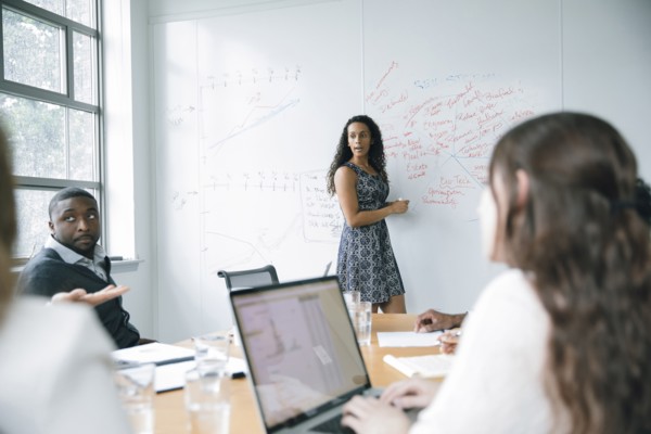 Businesswoman talking at whiteboard in meeting