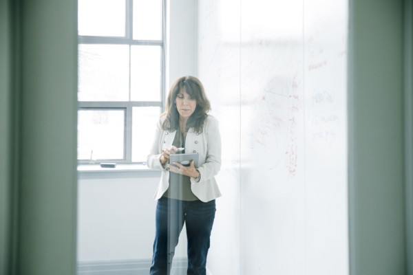 Caucasian businesswoman holding digital tablet near whiteboard