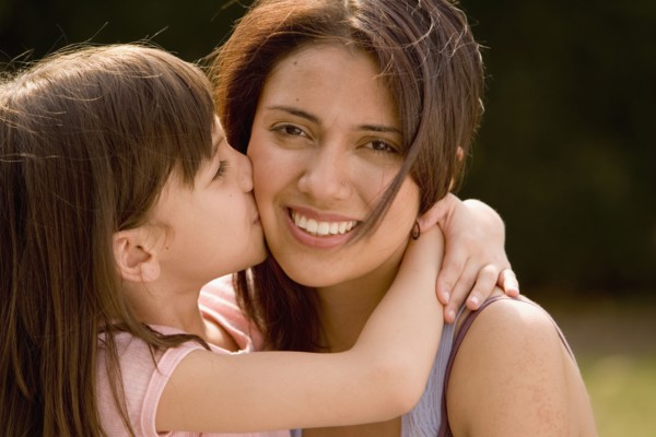 Hispanic girl kissing mother on cheek