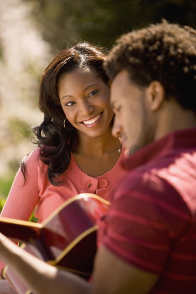 African American man playing guitar for girlfriend