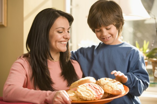 Hispanic mother and son holding plate of cookies