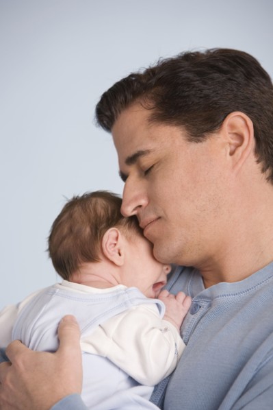Hispanic father hugging baby