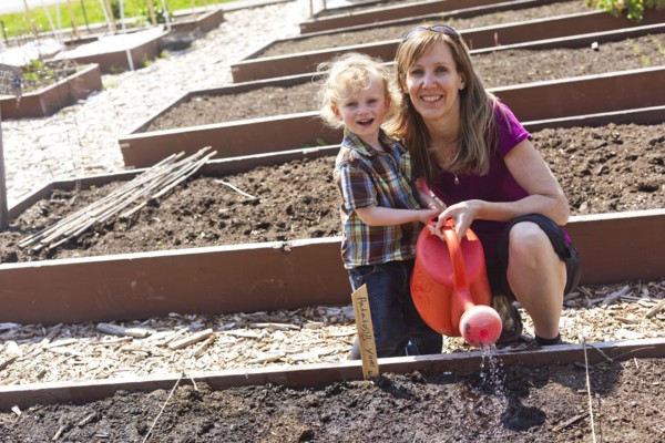 Caucasian mother and son watering plants in garden