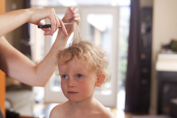 Caucasian mother cutting hair of son