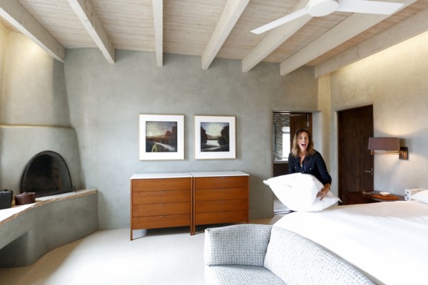 Laughing Caucasian woman holding pillow in bedroom