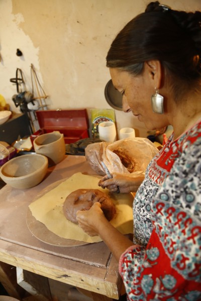 Mixed race woman shaping clay mask in art studio