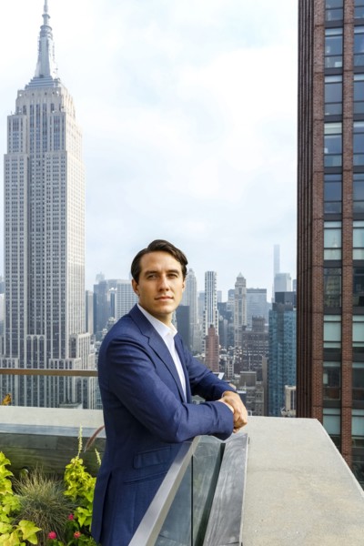 Portrait of serious Caucasian businessman leaning on urban rooftop