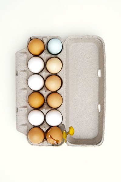 Colored eggs and one broken egg in carton