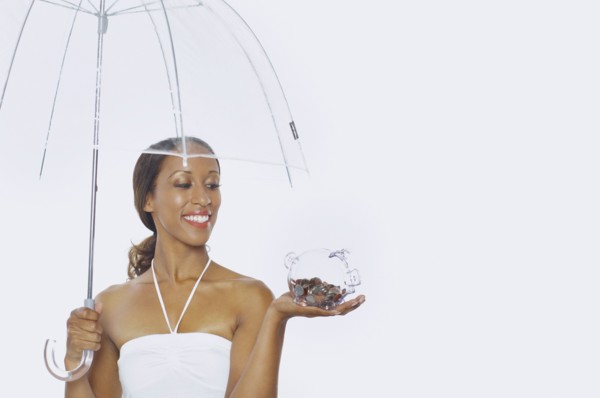 Young woman holding a piggy bank and an umbrella