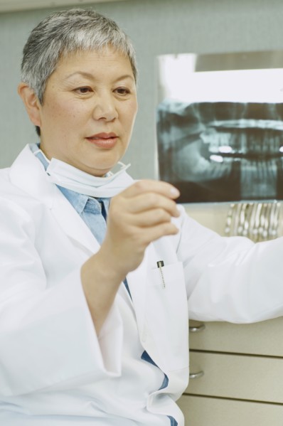 Senior Asian female dentist looking at x-rays