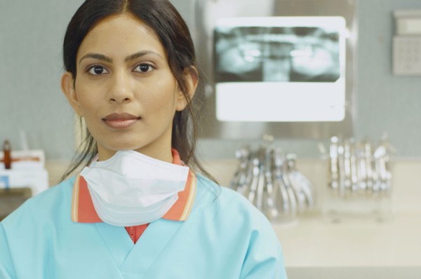 Indian female dental assistant next to x-rays