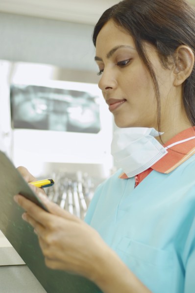 Indian female dental assistant writing on chart