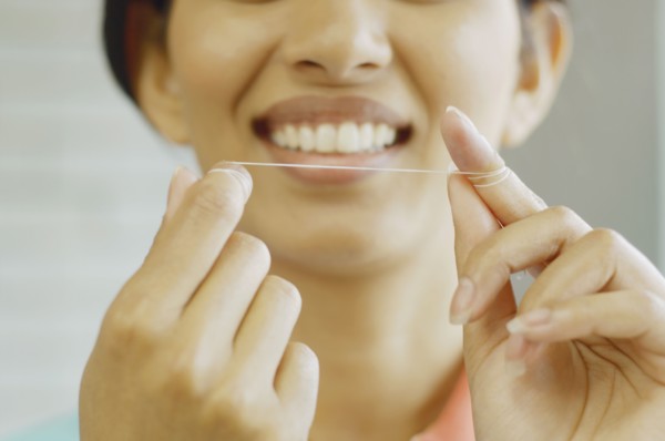 Woman smiling and holding dental floss